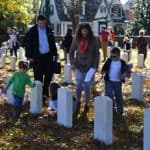 Family places American flags in front of American veteran graves