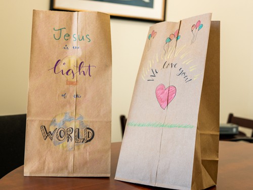 2 brown paper bags with different colorful drawings and phrases on them display on a table