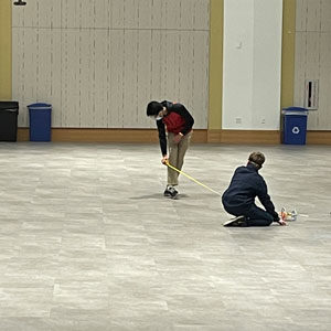 Two Highlands Latin School students take tape measure and measure a big room